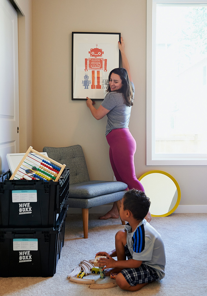 Woman hanging photo with a child on the floor