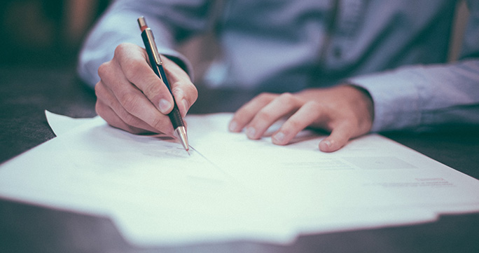 Man's hands signing paperwork